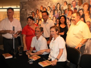 Na foto, da esquerda para direita, AC e Rô Barqueiro,Sidney Tobias, Aracy Bernardes e Laercio Sant´Anna em pé; Paulo Romeu e Lívia sentados  na mesa de autógrafos, onde estão livros e taças de prosecco.